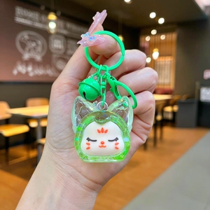Détail d'un porte-clés renard vert en bouteille acrylique avec petite clochette dorée