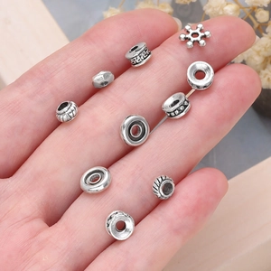 Detalle de cuentas espaciadoras de aleación plateada para joyas DIY sostenidas en la mano