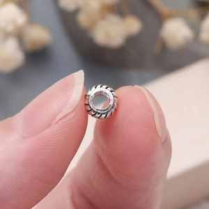Primer plano de cuentas espaciadoras de plata retro con textura de cuerda fina