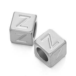Detailed macro view of two stainless steel silver cube beads with letter Z engraving