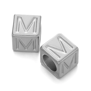 Detailed macro view of 7mm stainless steel silver cube beads with letter M engraving