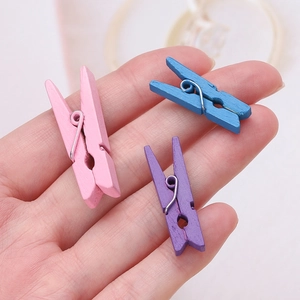 Handheld colorful mini wooden clips for DIY photos in pink, blue, and purple colors