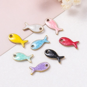 Gros plan de pendentifs poissons colorés en émail avec bords dorés pour la création DIY