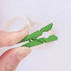 Close-up of a grass green wooden clip held by hand for DIY photo display projects