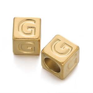 Macro view of a 7mm gold square stainless steel bead with engraved letter G for DIY jewelry