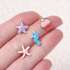 Gros plan de pendentifs colorés en émail avec étoile de mer et hippocampe sur métal doré
