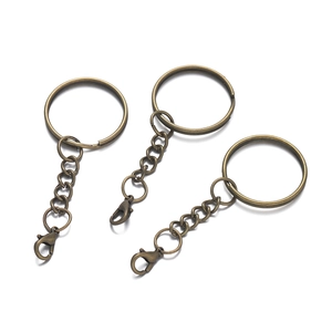 Three bronze metal keychains with split rings, chains, and lobster clasps on white background