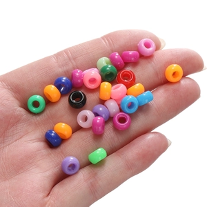 Gros plan de perles acryliques colorées 4x7mm tenues en main pour la création de bijoux