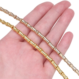 Detailansicht der bambusförmigen Zylinderperlen in Gold und Silber auf der Hand