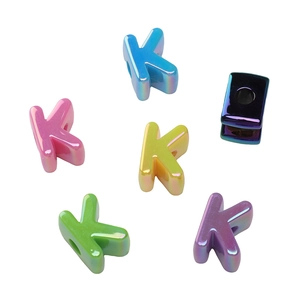 Dettaglio macro di perle a forma di K in acrilico placcato UV con finitura arcobaleno