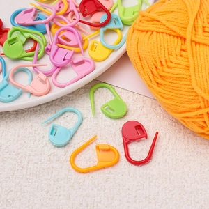 Macro shot of colorful plastic safety pins for knitting marking on a white texture background