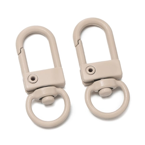Close-up of two matte beige 32mm swivel lobster clasps for DIY bag accessories
