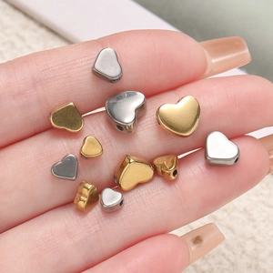Makro-Detail von herzförmigen Edelstahl-Abstandsperlen in Gold und Silber für DIY-Schmuck