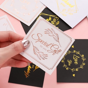 Close-up of elegant black and white cards with gold foil patterns in hand