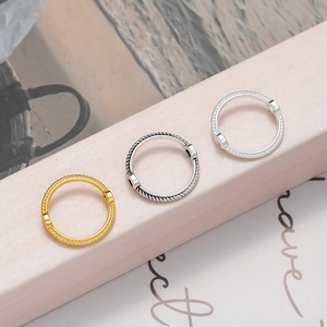 Gros plan sur trois anneaux en métal torsadé finitions or, argent et noir pour bijoux