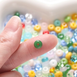Macro view of 3x6.5mm green glass rondelle bead held on fingertip for DIY jewelry making