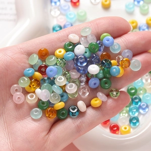 Close-up of hand holding colorful 3x6.5mm glass abacus beads for DIY jewelry making