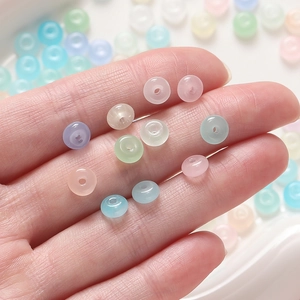Close-up of hand holding colorful pastel 3x6.5mm glass beads for DIY jewelry making