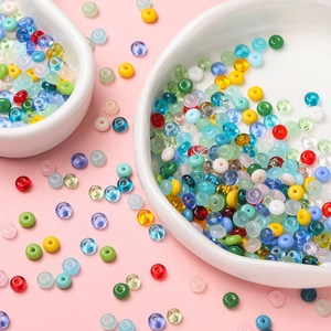 Flat colorful glass beads for DIY phone chains and bracelets on white ceramic dishes