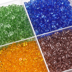 Close-up of colorful 3x6.5mm glass abacus beads in a four-grid clear storage box