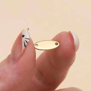 Macro shot of an oval polished gold stainless steel connector tag with dual holes for DIY