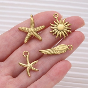 Golden sea star and sun charms held in hand to show scale for DIY jewelry making