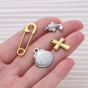 Detailed close-up of DIY sea turtle and shell charms held to show scale and metallic shine