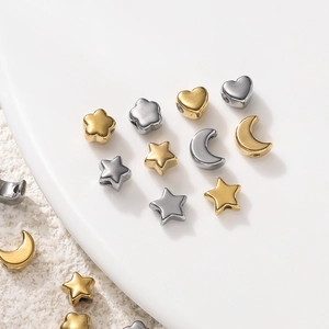 Close-up of gold and silver stainless steel spacer beads in star moon and heart shapes