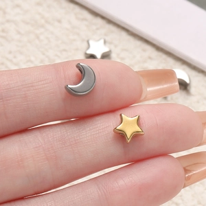 Detailed macro view of tiny polished moon and star beads held on a fingertip