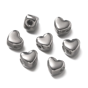 Detailed view of heart-shaped stainless steel spacer beads with polished surface and holes