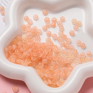 Gros plan de perles en verre translucide rose pâle 3x6mm pour la création de bijoux DIY