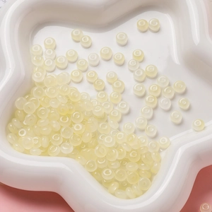 Gros plan de perles de verre 3x6mm crème pour création de bijoux dans un plat