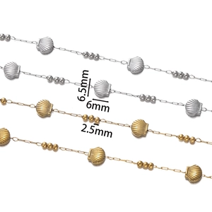 Close-up of gold and silver shell charms and round beads on stainless steel chains