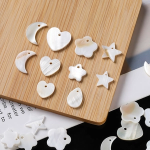 Macro detail of natural white shell charms in heart and star shapes with pre-drilled holes