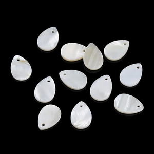 Macro view of teardrop natural shell charms with iridescent luster on black background