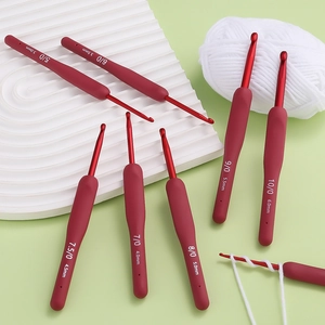 Ergonomic aluminum crochet hooks 3.0-6.0mm with red silicone handles on wave board