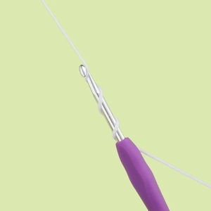 Close-up of a purple ergonomic handle crochet hook weaving white cotton thread