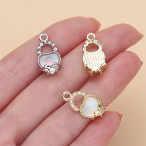 Dettaglio dei ciondoli a cuore DIY con fiocco, strass e perle dall'effetto iridato