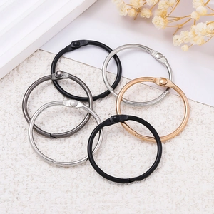 Close-up of metal binder rings in black, silver, gold, and gunmetal finishes on white surface
