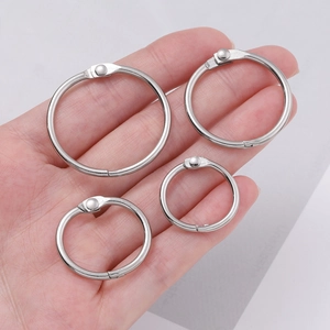 Detailed comparison of four different sizes of silver metal binder rings held in hand
