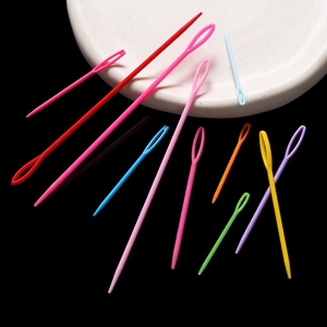 Colorful plastic large-eye sewing needles in multiple sizes for DIY knitting on a white plate