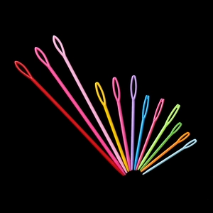 Colorful plastic large-eye sewing needles in various sizes on a black background