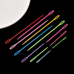 Colorful large-eye plastic sewing needles in various sizes set on a dark background