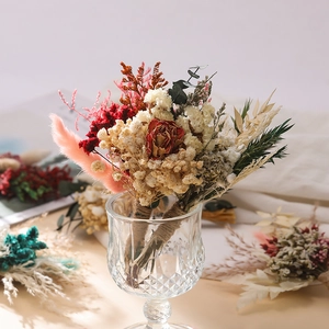 Mini dried flower bouquet with red roses and white baby's breath in a glass vase