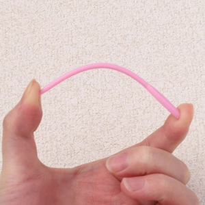 Close-up showing the high flexibility and bending durability of the pink plastic sewing needle
