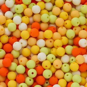 Macro detail of 6mm matte acrylic beads in mixed warm colors for DIY jewelry making