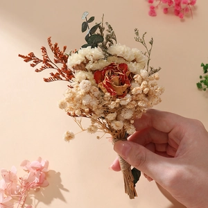 Detail of mini dried flower bouquet with red rose, baby breath, and eucalyptus tied in twine