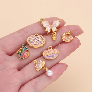 Pink and purple enamel butterfly and lotus charms held in hand for DIY jewelry making