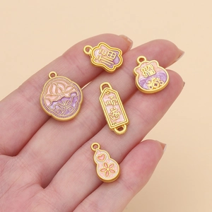 Macro detail of pink and purple enamel butterfly and gourd charms for DIY jewelry making