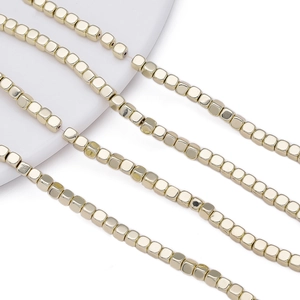Close-up of golden cubic hematite beads with metallic luster for DIY jewelry making